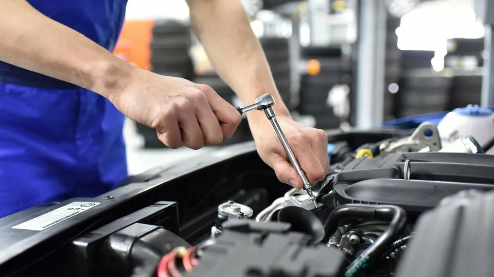 Automechaniker repariert an einem Fahrzeug im Motorraum